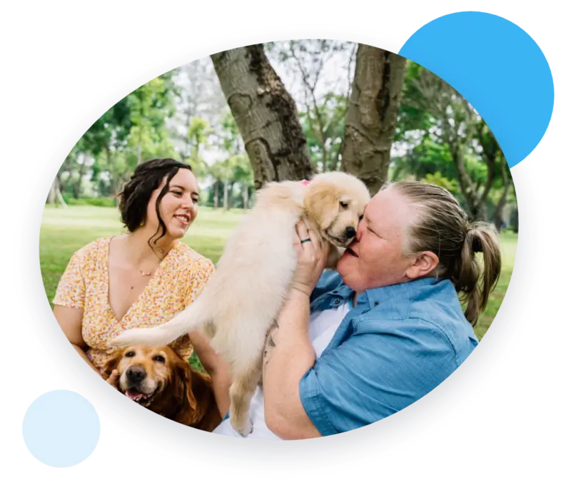 Happy couple cuddling their new golden retriever puppy in the park